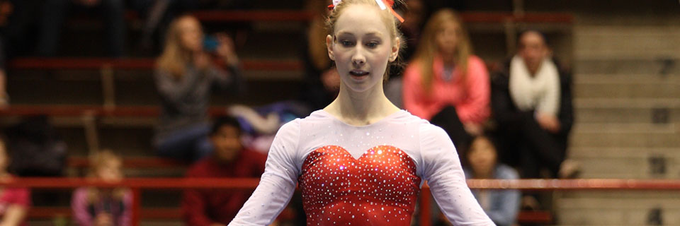 A student gymnast focusing as she performs.
