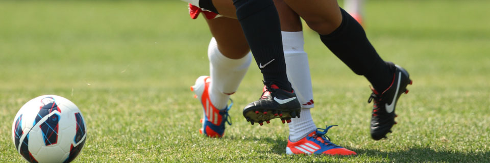 Soccer players kicking a soccer ball.