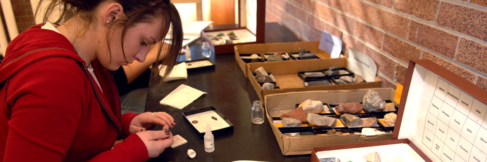 A student studies various rocks closely.