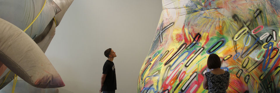 People gazing at a large rainbow colored art piece.