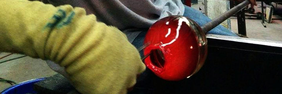 A student working with glass in Illinois State's glass blowing studio.