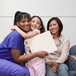 A nursing student is hugged by a smiling child and mom.